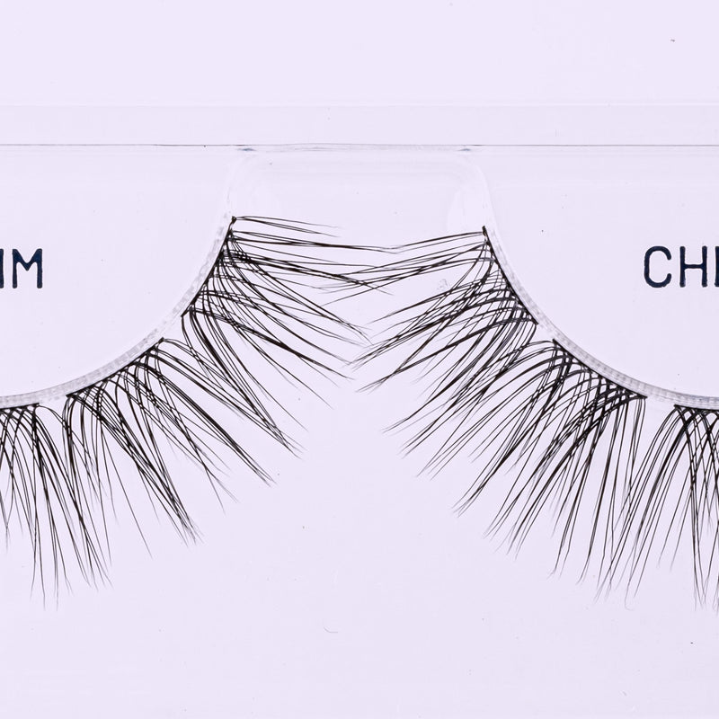 Close-up of Lilac St. lash extensions arranged in a curved tray, showing varied lengths and fine tapered fibers.